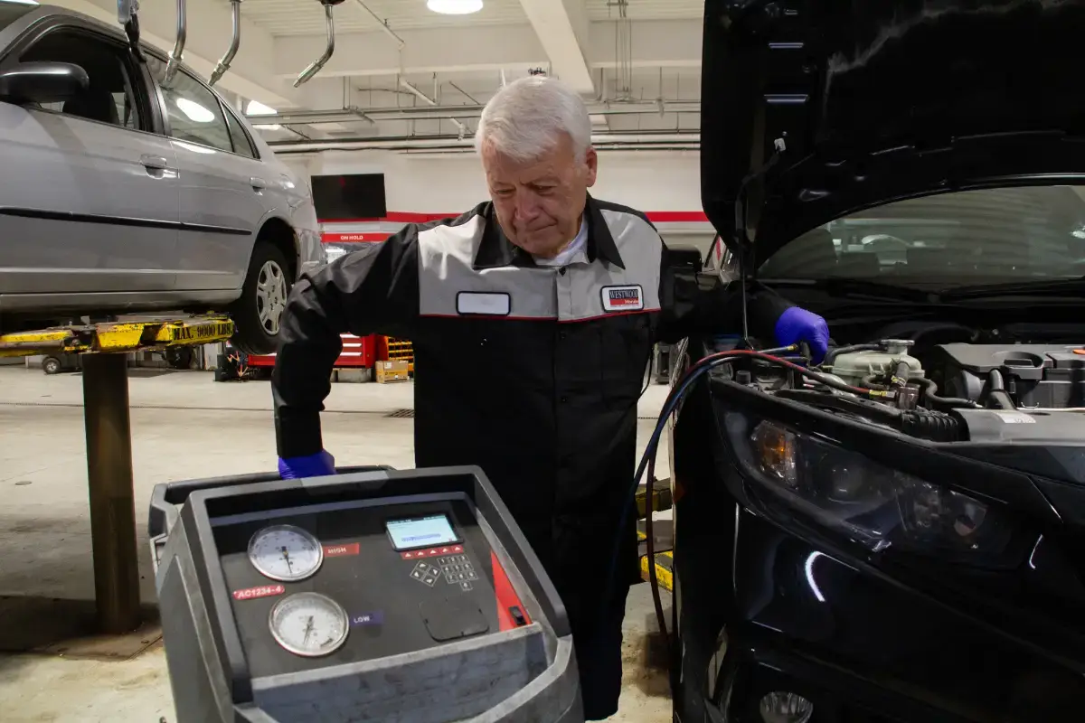 Auto repair technician inspecting a vehicle in the service bay at WestWoodHonda Auto repair technician inspecting a vehicle in the service bay at WestWoodHonda