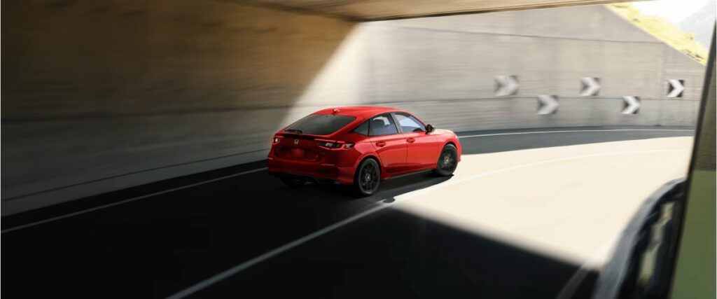2026 Honda Civic Hybrid rear view of red car driving through a curved tunnel
