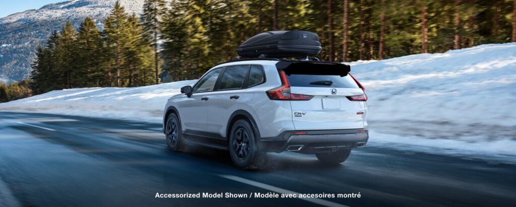 2027 Honda CR-V rear view with roof box driving on a snowy road